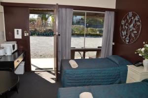 Habitación de hotel con cama y puerta corredera de cristal en Warwick Motor Inn, en Warwick