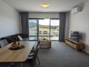 a living room with a table and a couch and a television at Serenity at Stromlo 2bd 1br at Wright in Weston Creek