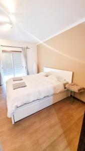 a bedroom with a white bed and a chair at Cozy Rooms Vila do bispo in Vila do Bispo