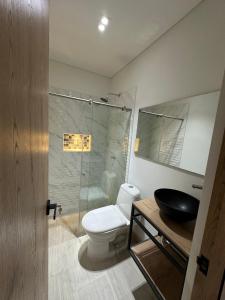 a bathroom with a toilet and a glass shower at Hotel La Casona San Sebastian in Doradal