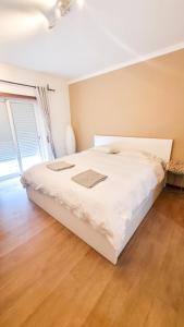 een wit bed in een slaapkamer met een houten vloer bij Cozy Rooms Vila do bispo in Vila do Bispo