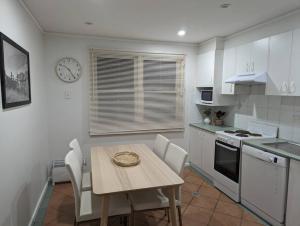 cocina con mesa, sillas y reloj en Comfortable Home 3bdr Nr Kingston and Fyshwick en Fyshwick