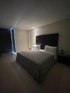 1 dormitorio con 1 cama grande con sábanas y almohadas blancas en Diverxo Hotel & Villas, en Tuxtla Gutiérrez