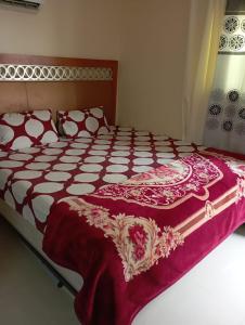 Una cama con un edredón rojo y blanco. en luule, en Al Ain