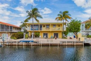 a yellow house on the water with palm trees at Pelican Landing in Islamorada