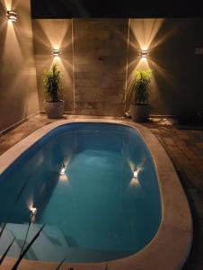 uma piscina à noite com dois vasos de plantas em Casa das posses para 8 pessoas em Serra Negra