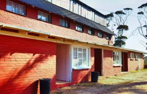 un edificio in mattoni rossi con porta e finestre bianche di Moonsong Accommodation & Camping a Plettenberg Bay