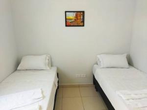 Kitnet 2 - próximo ao centro de Jacareí في جاكاري: سريرين في غرفة مع صورة على الحائط