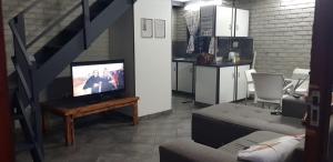 a living room with a tv on a table and a kitchen at Happy Haven in Welkom