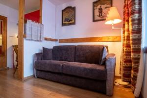 a couch sitting in a living room with a lamp at Lovely apartment with balcony in Alpe d'Huez - Welkeys in LʼHuez