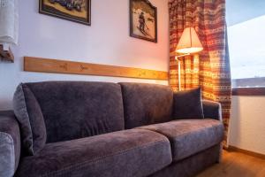 a couch sitting in a living room next to a window at Lovely apartment with balcony in Alpe d'Huez - Welkeys in LʼHuez