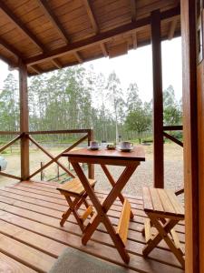 a wooden deck with a table and two benches at Pousada Doce Aconchego - Grão Pará - Aiurê in Aiuré