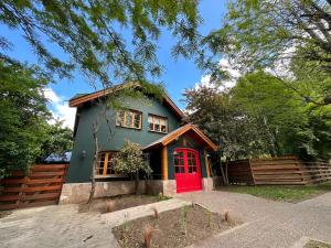 a house with a red door and a fence at Warthon Hostel in San Martín de los Andes