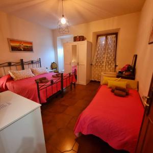 2 Betten in einem Zimmer mit roter Bettwäsche und einer Küche in der Unterkunft A Collodi Io & Mamma in Collodi