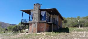 une maison en briques avec un balcon sur une colline dans l'établissement Utopía - Cabaña de Montaña, à Las Juntas