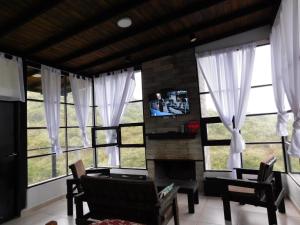 a living room with large windows and a tv at Utopía - Cabaña de Montaña in Las Juntas