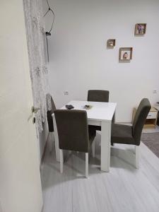 een witte eettafel met stoelen en een witte muur bij Apartman “Sanja” in Pirot