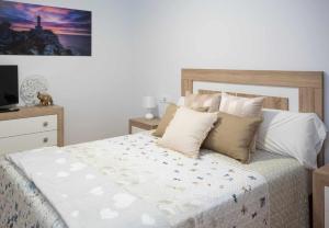 um quarto com uma cama com almofadas e uma televisão em AG Miramar Malpica x4 vistas playa Costa da Morte em Malpica de Bergantiños