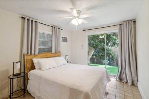 a bedroom with a bed with a ceiling fan and a window at Beach Bungalows By The Sea 3 in Cocoa Beach