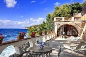 een patio met een tafel en stoelen en de oceaan bij Vera ed il Vervece by Gocce On the Sea in Massa Lubrense