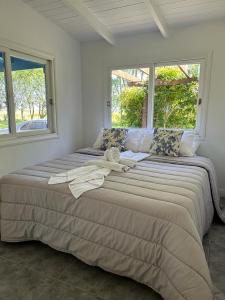 uma cama grande num quarto com duas janelas em El LUCERITO em Mar de Ajó