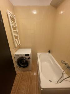 a bathroom with a washing machine and a tub at Comfort Stay Apartment - Free Parking & Wi-Fi in Chiajna +9 photos