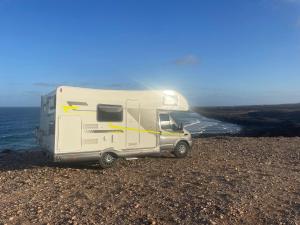 a white camper parked on the rocks near the ocean at Autocarabana Ford trigano in Arrecife