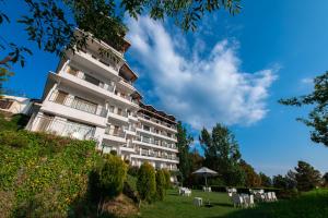 a tall white building with chairs and an umbrella at Ekant Retreat Resort in Chail