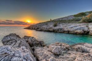a sunset over the ocean with rocks in the water at La Petite Calanque in Marseille