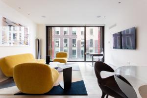 a living room with yellow chairs and a glass table at Designer Apartment in Mayfair/Regent Street in London