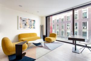 a living room with yellow chairs and a piano at Designer Apartment in Mayfair/Regent Street in London