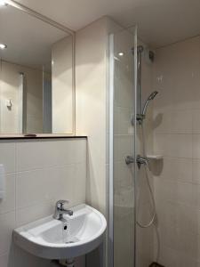 a white bathroom with a sink and a shower at FASTHOTEL ROISSY CDG SUD - Claye Souilly in Claye-Souilly