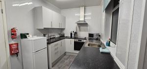 a white kitchen with a sink and a refrigerator at 8 Suffolk street by Prestige Properties SA in Roose