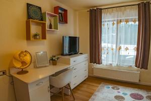 Zimmer mit einem Schreibtisch, einem TV und einer Kommode in der Unterkunft Casa Maxim - Locuință privata la poalele masivului Straja in Lupeni