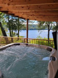 a hot tub on a deck with a view of the water at Nelson Warm Log Cabin with Private Hot Tub in Rivière-Rouge