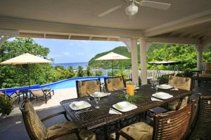 a dining table on a patio with a view of the ocean at Beautiful 5-Bedroom Villa Ashiana in Marigot Bay villa in Marigot Bay