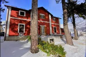 ein rotes Haus mit Bäumen im Schnee in der Unterkunft Antico Chalet Mini Momosa in Ovindoli