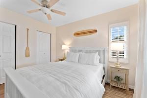 a white bedroom with a bed and a ceiling fan at Redington Beach Bungalow in St. Pete Beach