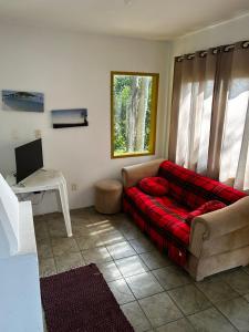 uma sala de estar com um sofá vermelho em frente a uma janela em Casa Sambaqui beira mar em Florianópolis