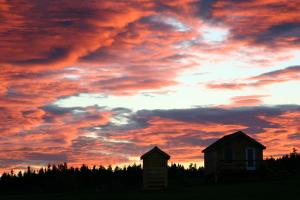 una puesta de sol con un edificio y una casa en Chalets Nature Océan en Perce