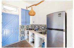 cocina con puertas azules y nevera de acero inoxidable en La Bocana Surf House, en Santa María Huatulco