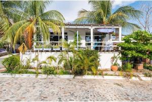 a white house with palm trees in front of it at La Bocana Surf House in Santa Cruz Huatulco