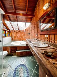 uma casa de banho com 2 lavatórios, uma banheira e um espelho. em Casa a 180m da Praia do Toque Toque Pequeno SP em São Sebastião