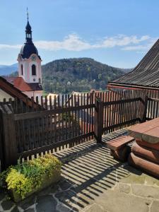 a wooden fence with a clock tower in the background at Štramberk V Kútě in Štramberk