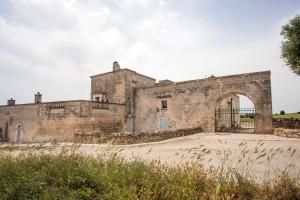un vecchio edificio in pietra con un cancello di fronte di Masseria Angiulli Piccolo Contrada Angiulli 74023 Grottaglie a Villa Castelli