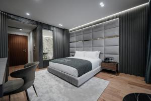 een slaapkamer met een bed, een bureau en een stoel bij Marinaj Hotel in Tirana