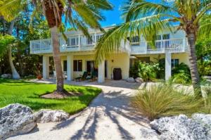 a white house with palm trees in front of it at Sunshine Place in Islamorada