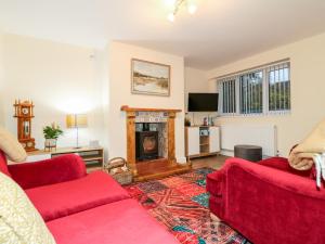 a living room with two red couches and a fireplace at 8 Church Lane in Checkley