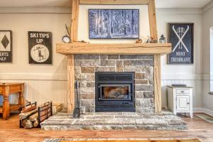 una sala de estar con chimenea de piedra con un manto en 124 Algonquin - Ski In Out Tremblant Mountainside Chalet, en Mont-Tremblant