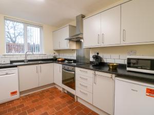 a kitchen with white cabinets and black counter tops at 8 Church Lane in Checkley